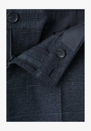 Donker wollen blazer met een gestructureerde stof, twee knopen, een ritszak en een gestikte voering. Subtiel geruit patroon zichtbaar.
