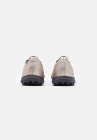 Baskets de sport gris clair avec une tige texturée, un dos arrondi et des accents violet foncé ; dotées d'une semelle robuste adaptée à l'adhérence.