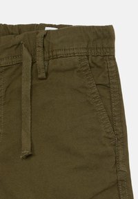 Calças de algodão verde-oliva com cintura elástica, cordão e bolsos laterais. Apresentam costuras visíveis e um tecido texturizado.
