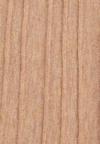 Tessuto a maglia beige con una texture a righe verticali, caratterizzato da leggere variazioni di colore e una forma morbida e allungata. Nessun accento particolare.