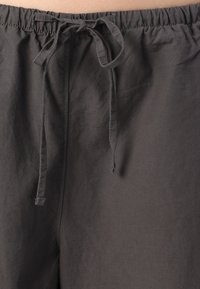 Zwarte katoenen shorts met een elastische tailleband en een verstelbare trekkoord. De stof is glad en heeft een lichtgewicht textuur.