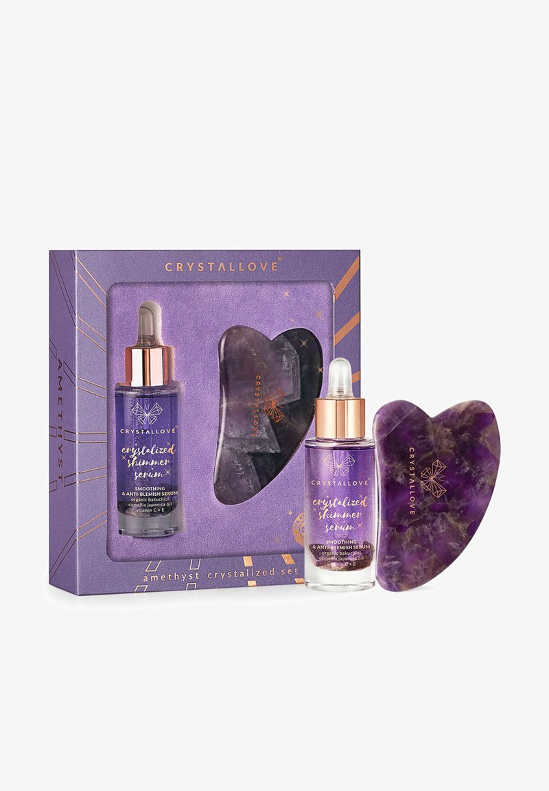 Ensemble Amethyst Crystallove comprenant deux flacons de sérum en cristal violet et un outil en cristal en forme de cœur assorti, le tout dans une boîte décorative.