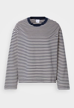 Garā piedurkņu kreklis ar apaļu kakla izgriezumu baltā un tumši zilā svītrā. Iezīmēts ar vienkrāsainu tumši zilu kakla izgriezumu un brīvu griezumu ar sānu šķirbēm apakšējā malā.