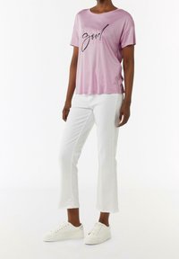 Camiseta de manga corta rosa claro con el texto "Siempre bien" en negro, combinada con pantalones blancos cortos y zapatillas blancas. Textura de tela suave.