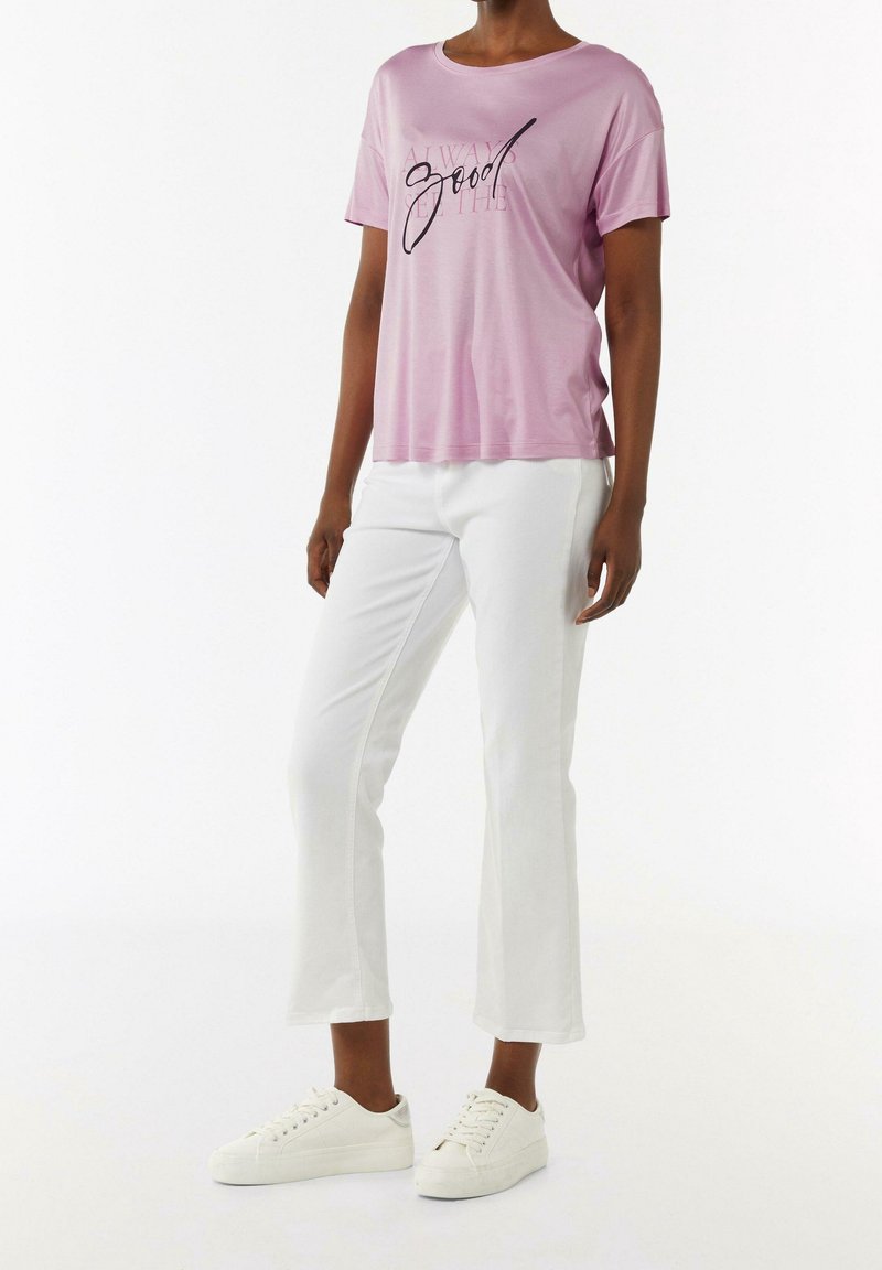 Camiseta de manga corta rosa claro con el texto "Siempre bien" en negro, combinada con pantalones blancos cortos y zapatillas blancas. Textura de tela suave.