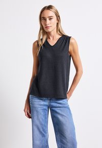 Top senza maniche grigio scuro con scollatura a V, realizzato in un materiale morbido. Abbinato a jeans in denim a gamba larga blu chiaro.