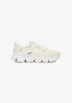 Kremowo‑fioletowy sportowy sneaker Reebok z teksturowaną cholewką z siateczki i grubą, segmentowaną białą podeszwą, widok z boku.