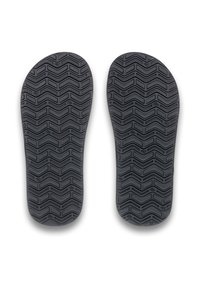Svarta gummisoles med ett zigzag-mönster, som visar en texturerad yta utformad för grepp och hållbarhet.