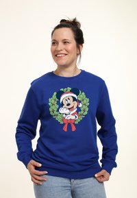 Sudadera azul de algodón con un gráfico de un personaje de dibujos animados rodeado de un diseño de corona. Puños y dobladillo acanalados.