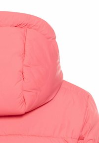 Lyserød pufferjakke med en høj, polstret krave. Stoffet ser glat og let ud, og har syninger langs sømmene.