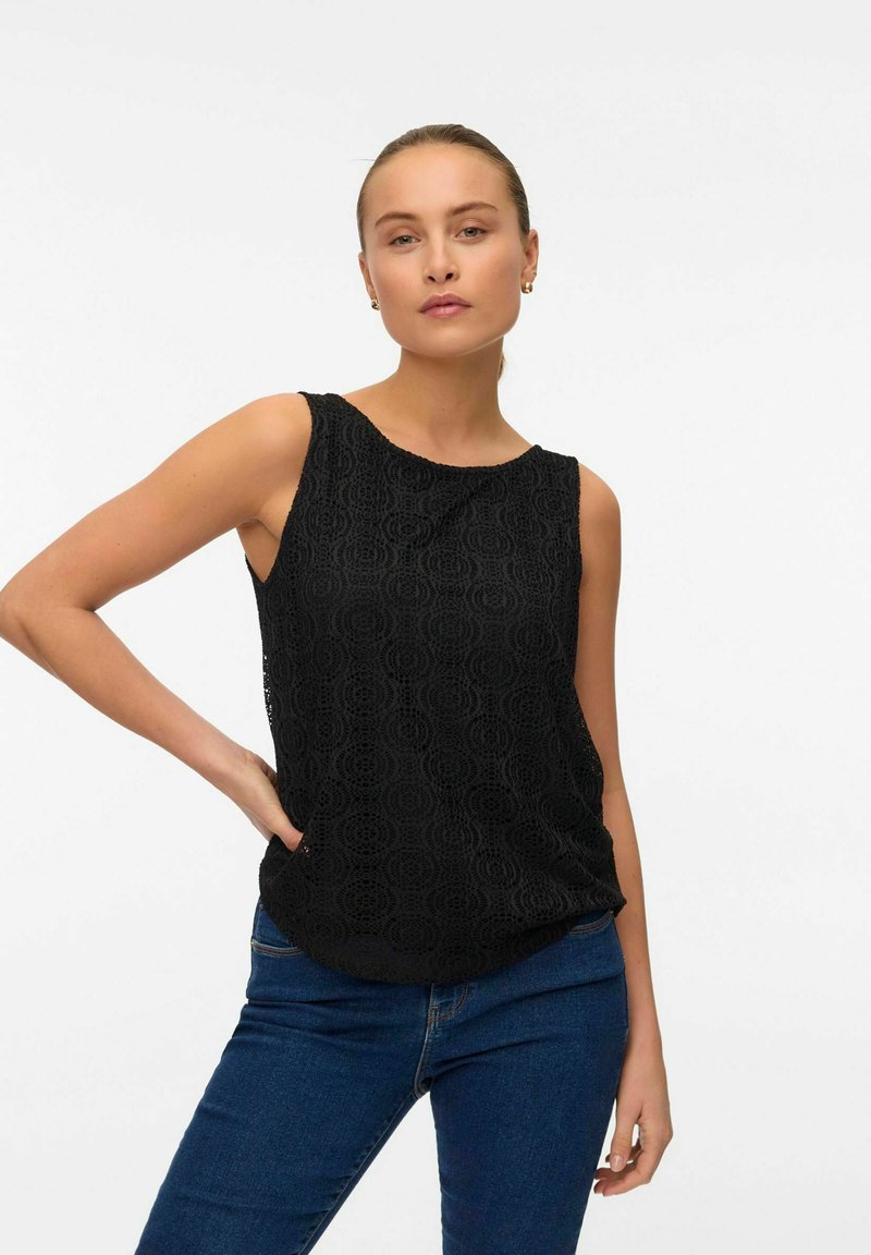 Czarna bezrękawnikowa bluzka z teksturowanym wzorem, z okrągłym dekoltem i luźnym krojem, w połączeniu z dżinsowymi spodniami.