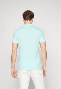 Lyse blå polo skjorte med korte ermer, som har en klassisk krage og subtile hel detaljer, paret med lyse shorts.