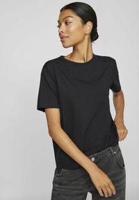 Must have kummargane lühikeste varrukatega T-särk puuvilla segus, ümmarguse kaeluse ja mugava fitiga, koos tumedate hallide teksadega.