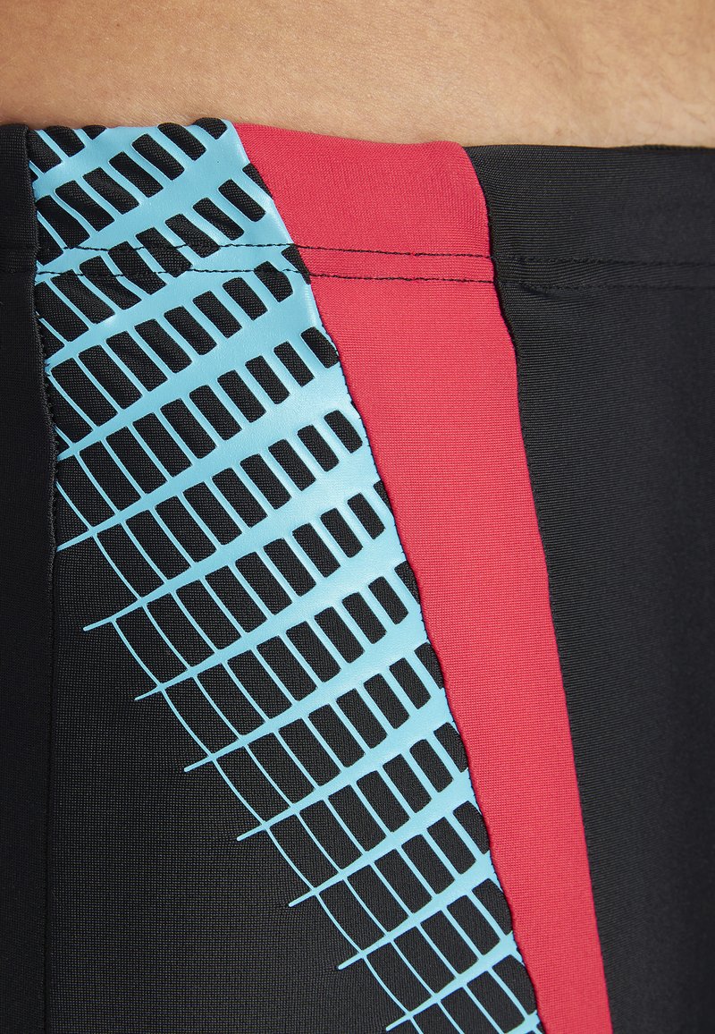 Czarne kąpielówki z bocznym wzorem w niebieską siateczkę i czerwonymi akcentami. Gładka tkanina z kontrastowymi wzorami.