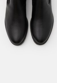 Black leather ankle boots with a smooth texture, rounded toe, elastic side panels, and a slightly raised rubber sole.
