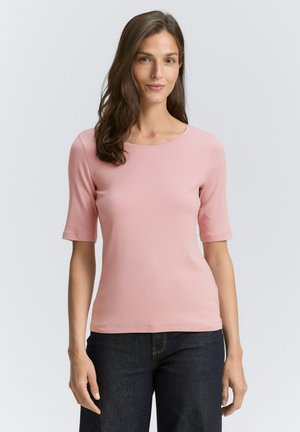 T-shirt rosa chiaro a maniche corte con scollatura rotonda, realizzato in tessuto morbido. Abbinato a jeans di denim blu scuro.