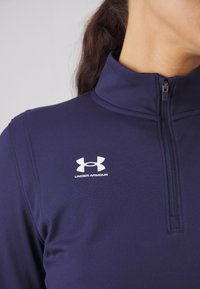 Námořnická čtvrtzipová mikina vyrobená z elastického materiálu, s vysokým límcem, jemným prošíváním a kontrastním bílým logem Under Armour.