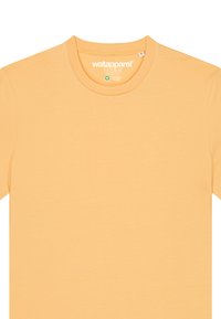 T-shirt court à manches courtes de couleur orange clair en tissu doux avec un col rond. Présente une étiquette de marque à l'intérieur du col.