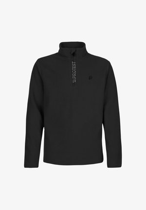 Garçon portant un bonnet noir, un haut à manches longues noir et un pantalon de neige noir et blanc à motifs, debout et regardant sur le côté.