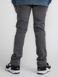 Jean gris con corte recto, que presenta bolsillos traseros y detalles de ligero desgaste, combinados con zapatillas negras y blancas.
