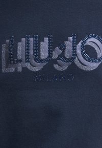 Felpa blu navy con il testo "LIU JO MILANO" decorata con vari toni di strass blu e accenti luccicanti.