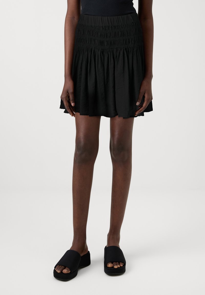 Μαύρη φούστα με στρώσεις και ελαστική μέση, κατασκευασμένη από ελαφρύ ύφασμα. Φοριέται με μαύρα παπούτσια πλατφόρμας.