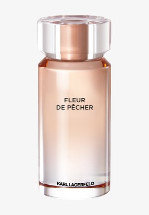 Korkea läpikuultava pullon muotoinen hajuvesipullo, jossa vaalea persikkaista nestettä, kirkas hiontakaulus, jossa tekstit "Fleur de Pêcher" ja "Karl Lagerfeld" pohjassa.