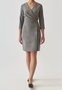 Grå omlottklänning med djup V-ringning, trekvartslånga ärmar och en figurnära silhuett. Mjuk textur, knälång med en ren avslutning.