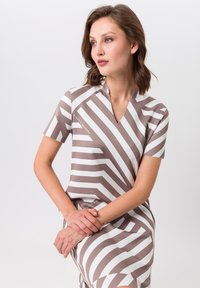 Robe à manches courtes avec un décolleté en V, conçue avec des rayures en zigzag marron et blanc, fabriquée dans un tissu léger et lisse avec une finition soignée.