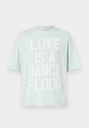 Camiseta de algodón color verde menta claro con texto en bloque blanco: "EL AMOR ES UNA PISTA DE BAILE." Cuello redondo y mangas cortas.