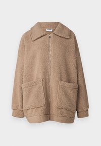 Fleece bunda v světle hnědé barvě s límečkem, plným zipem a dvěma předními kapsami. Měkká textura, oversized střih a žádné viditelné vzory.