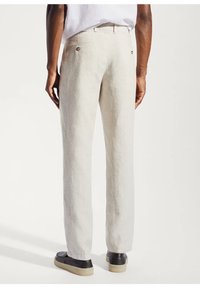 Pantaloni in lino beige chiaro con una vestibilità rilassata, dotati di una vita posteriore con due bottoni e tessuto testurizzato.
