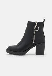 Black heeled ankle boot with a smooth synthetic upper, side zip closure with a circular pull, and a textured rubber sole.