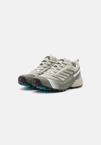 Lichtgrijze trailrun schoenen met een gemêleerde bovenkant van mesh, rubberen zool en turquoise accenten. Beschikt over een versterkte neus en een logo aan de zijkant.