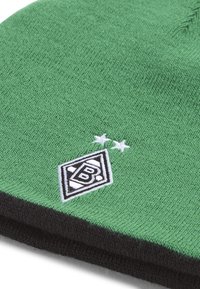 Bonnet tricoté vert avec un revers noir et un écusson portant un logo accompagné de deux étoiles brodées en blanc.