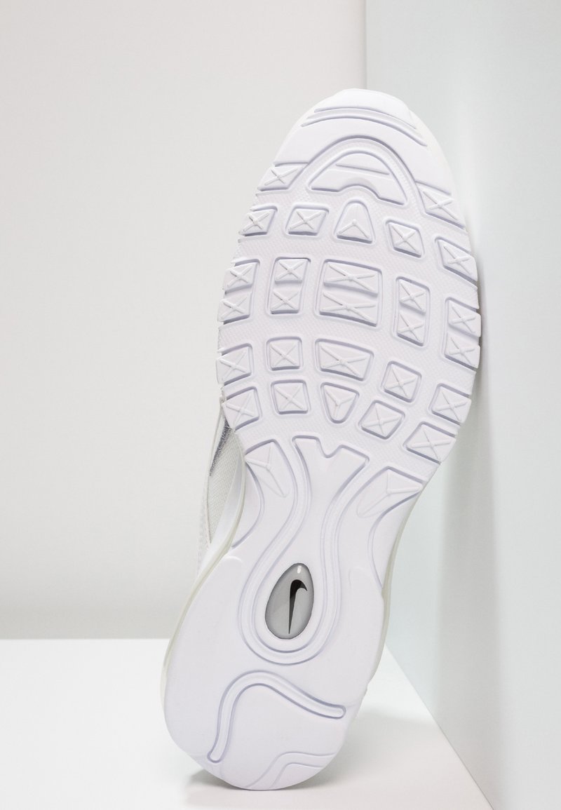 Semelle de basket blanche avec un caoutchouc texturé, présentant un motif distinctif, des formes courbées et une découpe de logo visible. Bords extérieurs lisses.