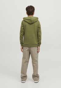 Sudadera color verde oliva con capucha ajustable, tela texturizada, puños acanalados, combinada con pantalones cargo beige que cuentan con bolsillos laterales.