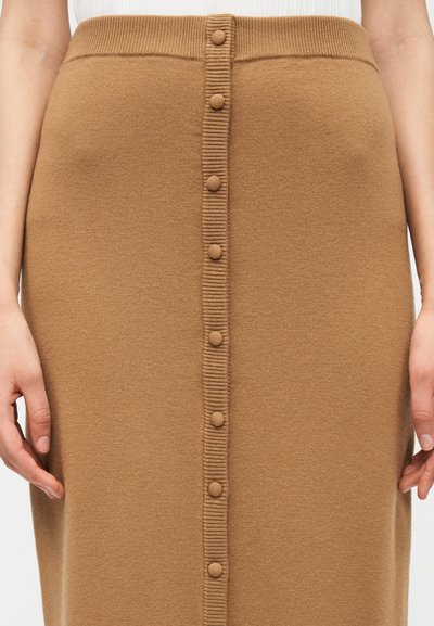 Πλεκτή καφέ φούστα με ίσια γραμμή, που διαθέτει μια σειρά από κουμπιά στο μπροστινό μέρος και ριμπ ζώνη στη μέση. Μαλακή υφή.