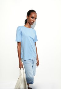 T-shirt en coton bleu clair à manches courtes, col rond, accompagné de shorts en denim clair à revers. Texture lisse et design décontracté.