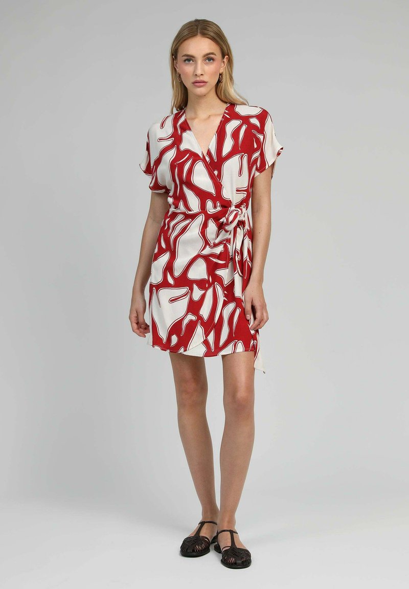 Robe enveloppante rouge et blanche présentant des motifs abstraits, des manches courtes et un lien sur le côté. Tissu doux avec une texture légère.