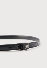 Črni usnjen pas s tanko zasnovo, z zaponko iz srebrnastega kovinskega materiala in reliefnim vzorcem. Gladek na otip s perforacijami za nastavitev velikosti.