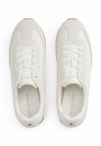 Un paio di sneakers bianche Tommy Hilfiger con lacci, accenti in suede e dettagli del logo sulla linguetta, sul lato, sulla soletta e sul tallone.