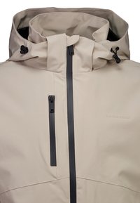 Lekka beżowa wodoodporna kurtka z wysokim kołnierzem, czarnym zamkiem błyskawicznym, regulowanymi sznurkami i subtelnym logo z przodu. Gładka tekstura.