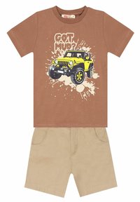 Bruine katoenen T-shirt met een gele grafiek van een off-road voertuig en de tekst "GOT MUD?", gecombineerd met tan katoenen shorts met achterzakken.