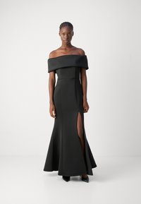 Robe noire décolletée avec un corsage ajusté, une jupe évasée et une fente haute. Tissu lisse avec une finition élégante et un design structuré.