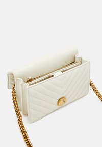 Borsa a tracolla in ecopelle bianca trapuntata con hardware dorato, tracolla a catena e chiusura con zip. Presenta un motivo a zig zag. Forma rettangolare compatta.