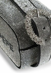 Bolso rectangular adornado con pedrería plateada, con base negra y una correa circular con detalles de pedrería. Textura detallada y brillo evidente.