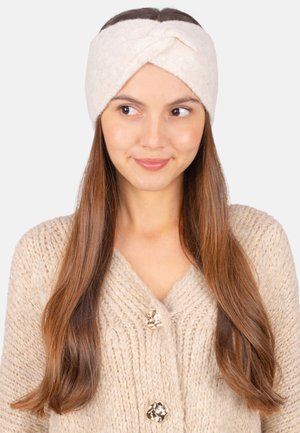 Cremfarbener Wollkopfbund mit einem gedrehten Design, getragen mit einer beigen Strickjacke mit großen, strukturierten Knöpfen. Glatte Textur, weiches Material.