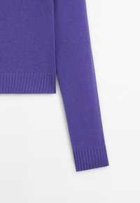 Manche de pull en maille violette avec poignets et ourlet côtelés sur fond blanc, montrant la texture et les détails du tissu.