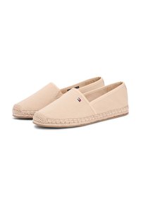 Espadrilles en toile beige avec une semelle en jute tressé et un détail de logo subtil. Bout arrondi et design à enfiler, présentant une texture lisse.